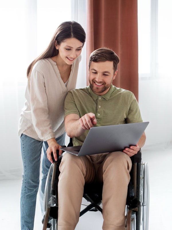 Man using a wheelchair looking at a laptop with a support worker