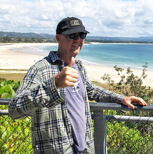 Man giving a thumbs up on a lookout above a beach