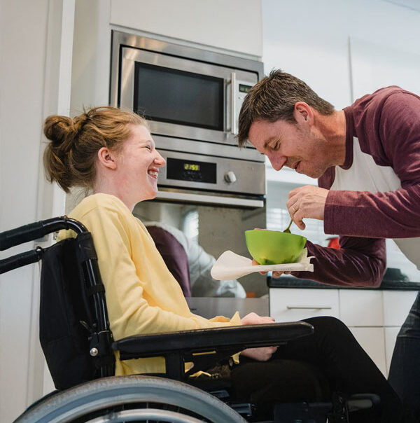Support worker and a person who uses a wheelchair preparing food together in a kitchen