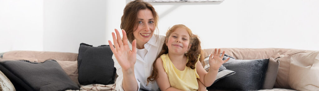 Woman and child waving from a couch