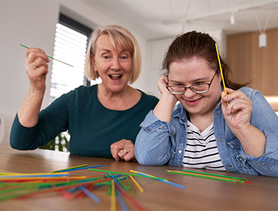 Two people laughing while playing a pick-up sticks game