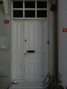 A white front door of a house with street numbers beside it