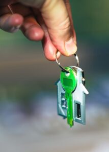 A hand holding house keys with a house-shaped keyring